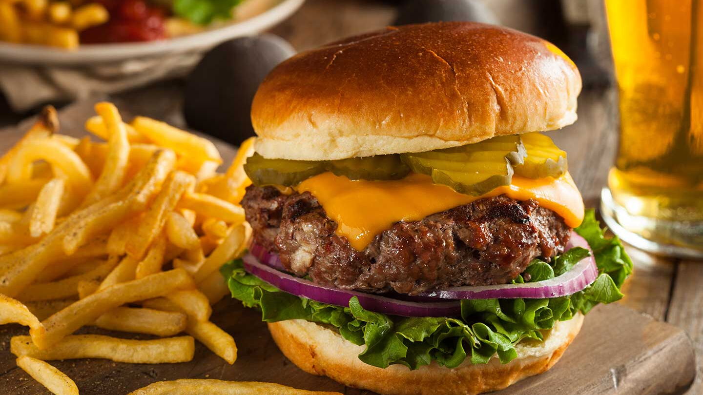 Foto eines Hamburgers, einer Portion Pommes Frites mit Ketchup und von einem Glas Bier