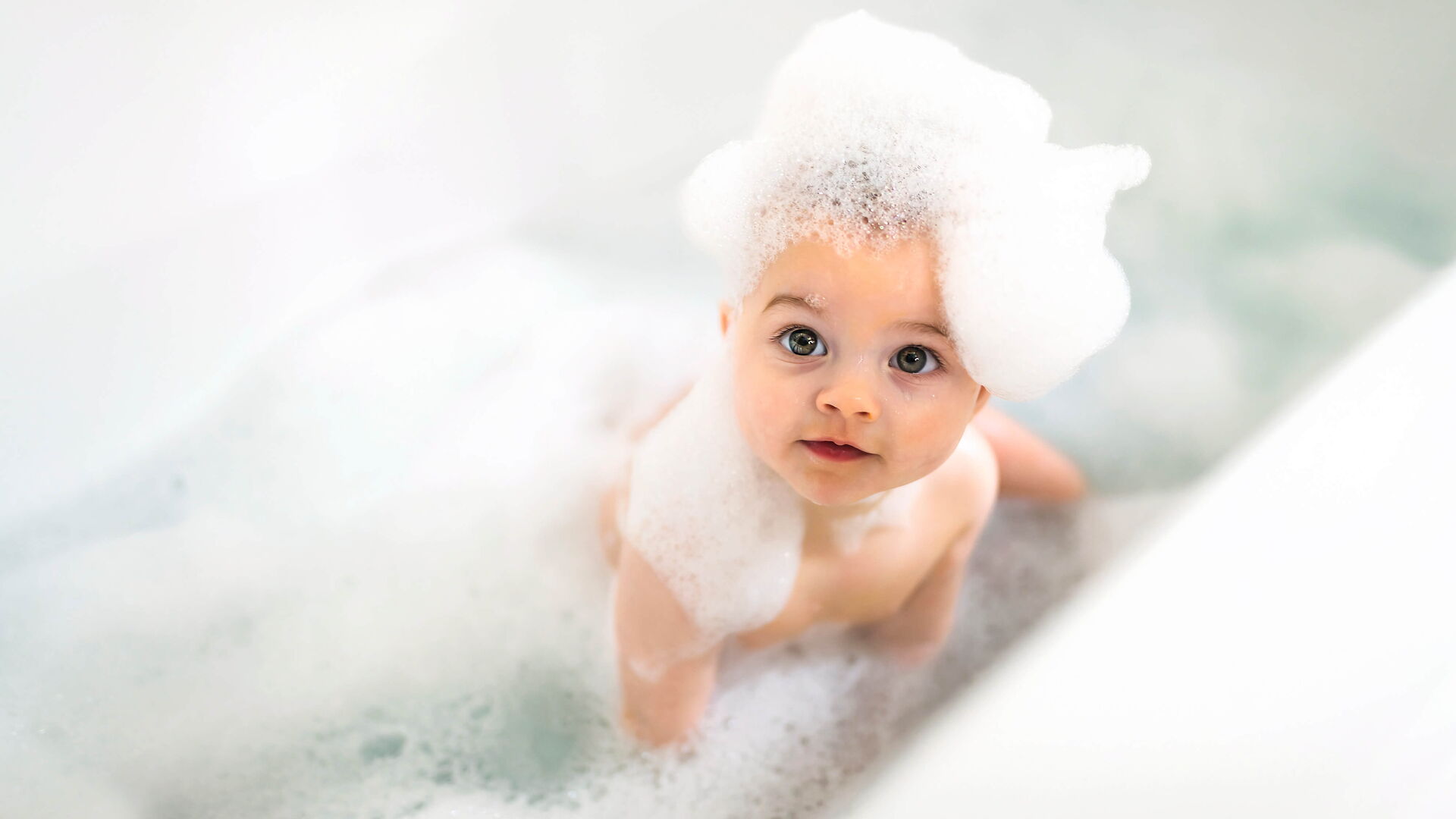 Baby mit Schaumkrone im Bad