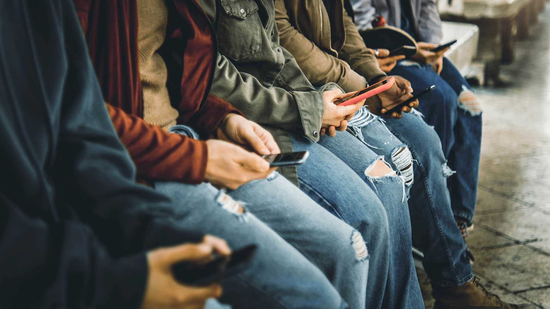 Eine Gruppe von 6 Menschen verwendet Smartphones. Der Bildausschnitt zeigt die Hände der dargestellten Personen.
