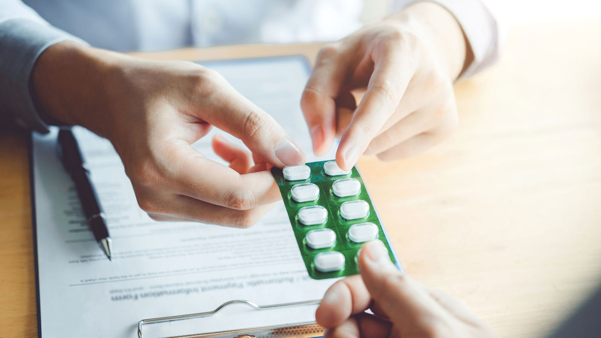 Ein Arzt überreicht seinem Patienten verschreibungspflichtige Tabletten.