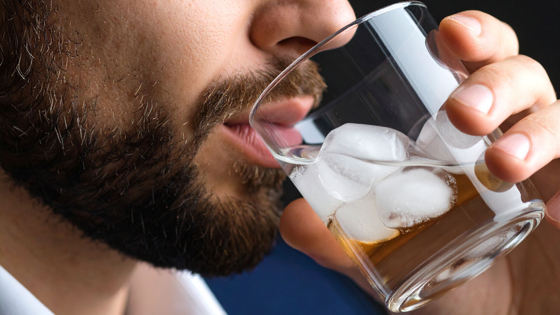 Ein Mann trinkt Alkohol aus einem Glas mit Eiswürfeln