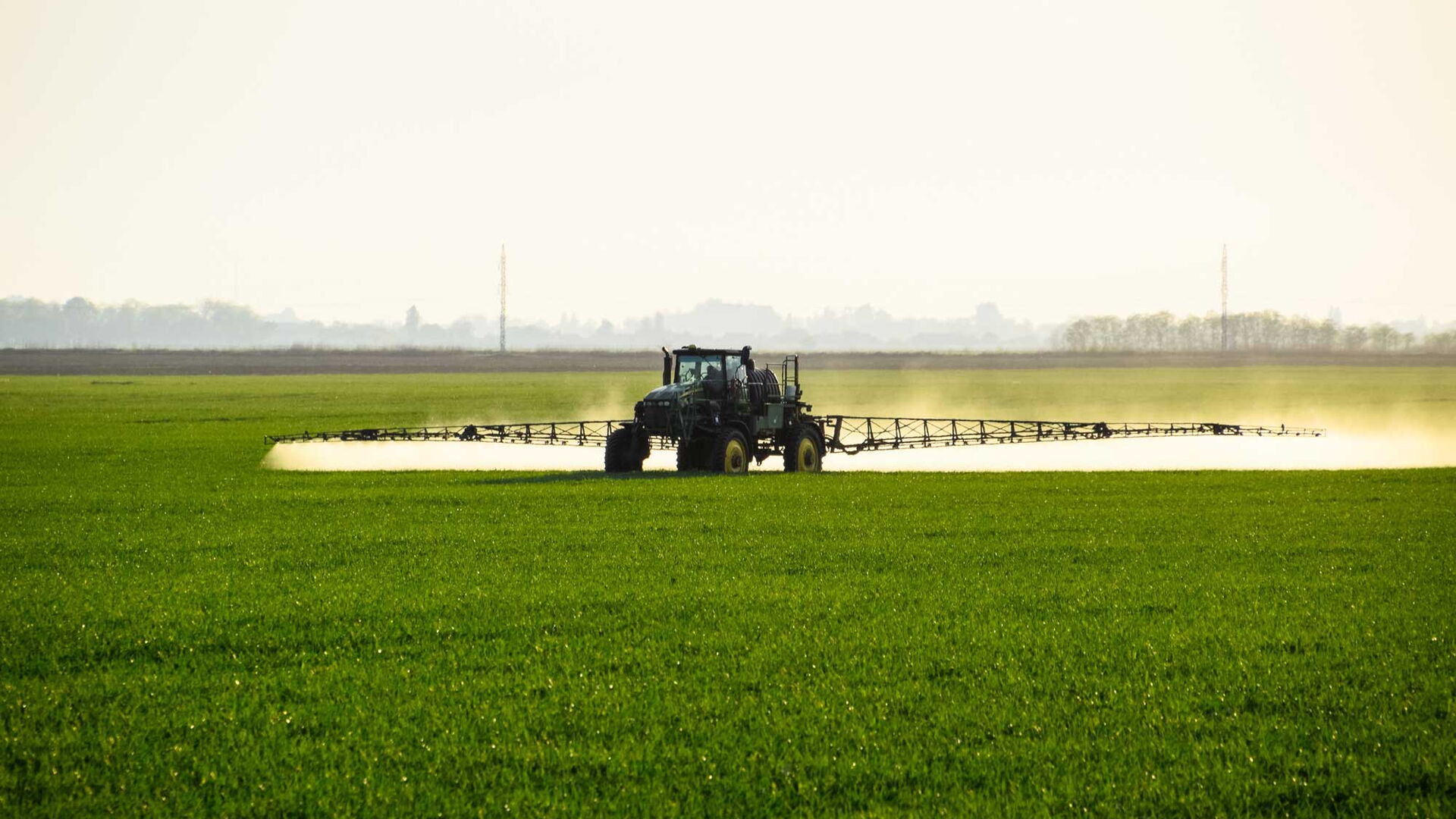 Eine Landmaschine verspritzt eine Flüssigkeit auf einem Feld.