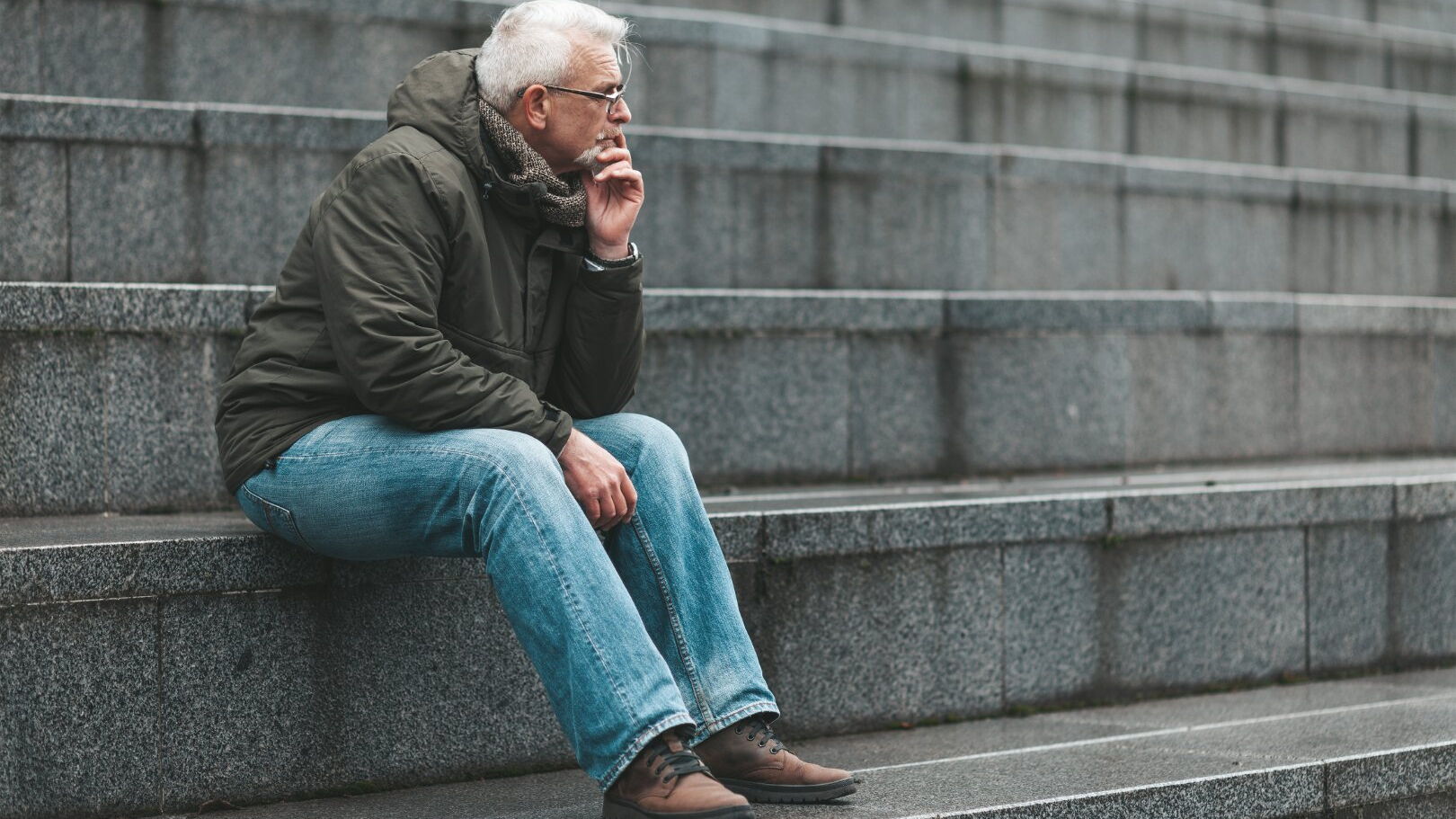 Ein Mann sitzt nachdenklich auf Treppenstufen im Freien.