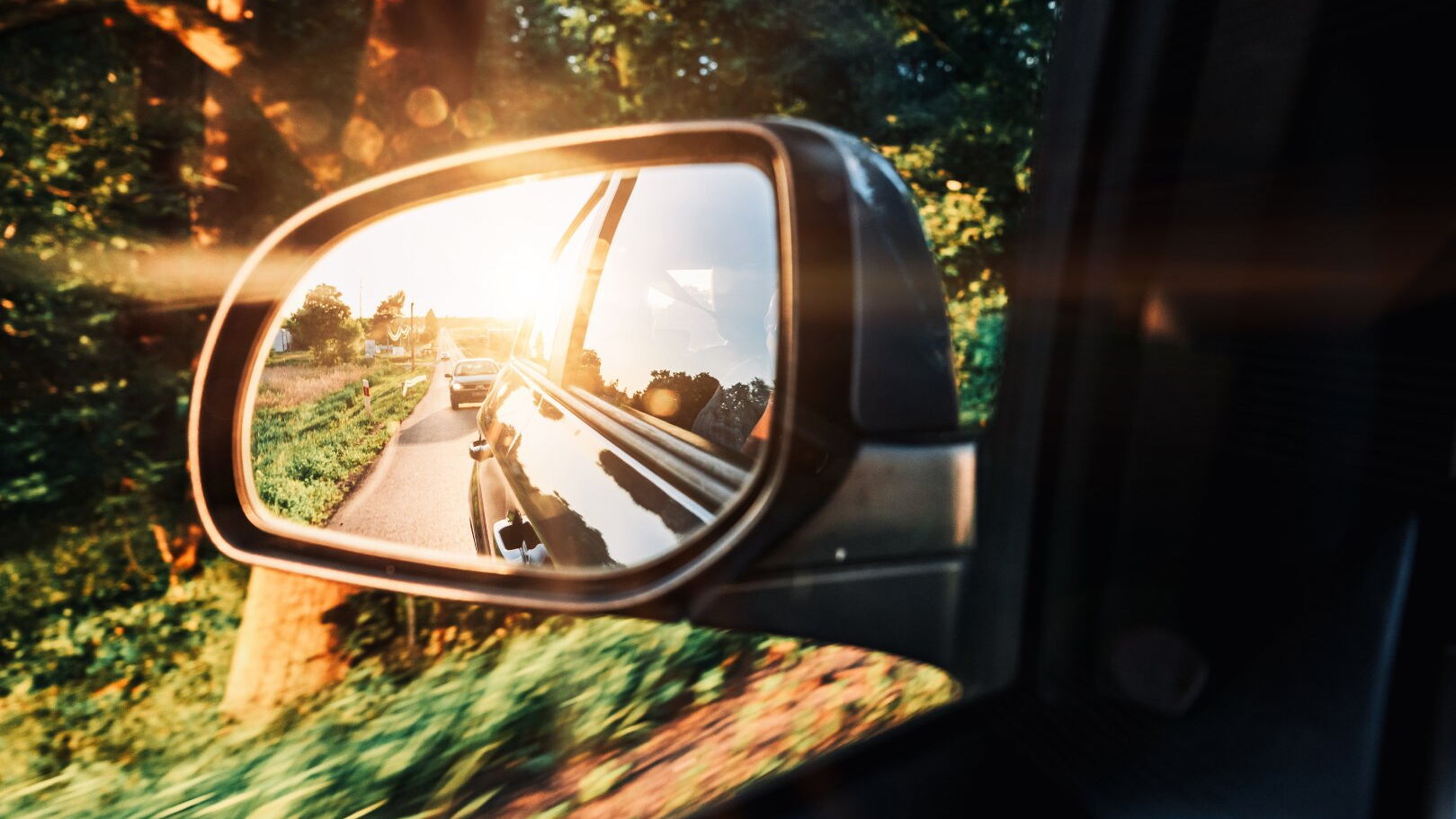 Im Seitenspiegel eines Autos spiegelt sich die Sonne