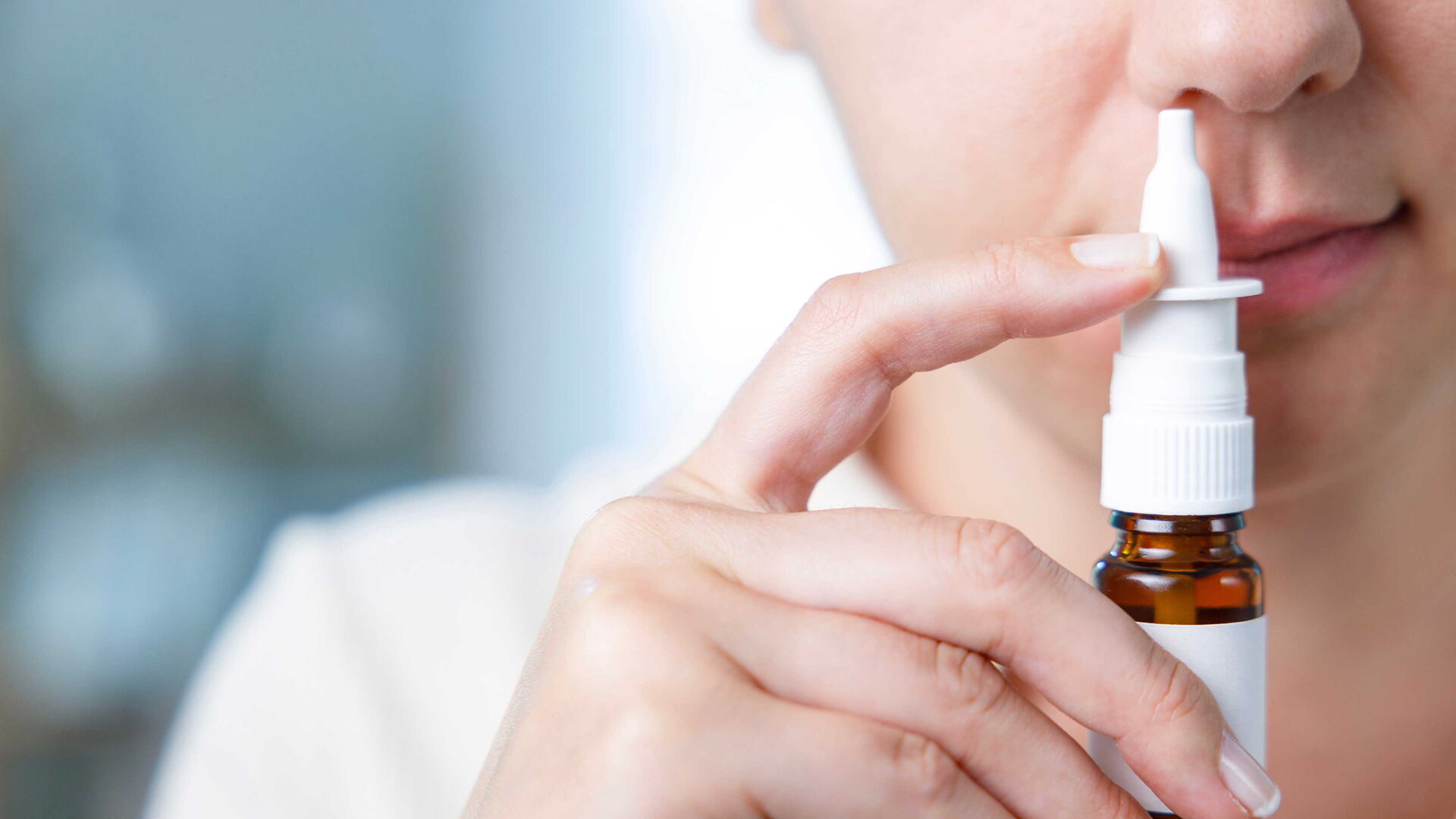 Eine weibliche Person verwendet Nasenspray.