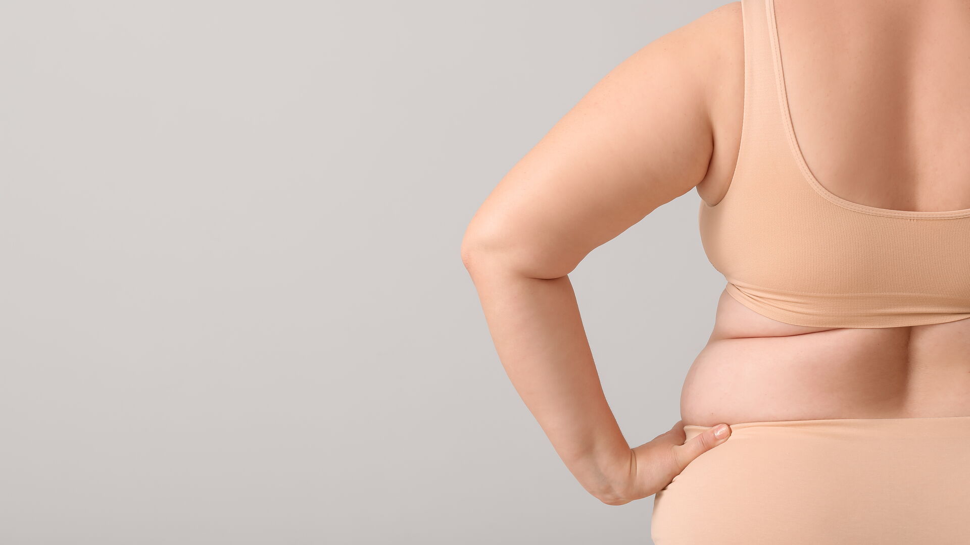 Übergewichtige Frau mit Celluliteproblem auf hellem Hintergrund
